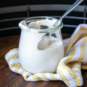 Spoon in a glass jar with sour cream inside and up the walls.