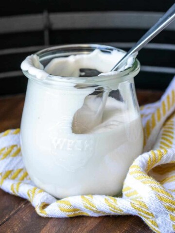 Spoon in a glass jar with sour cream inside and up the walls.