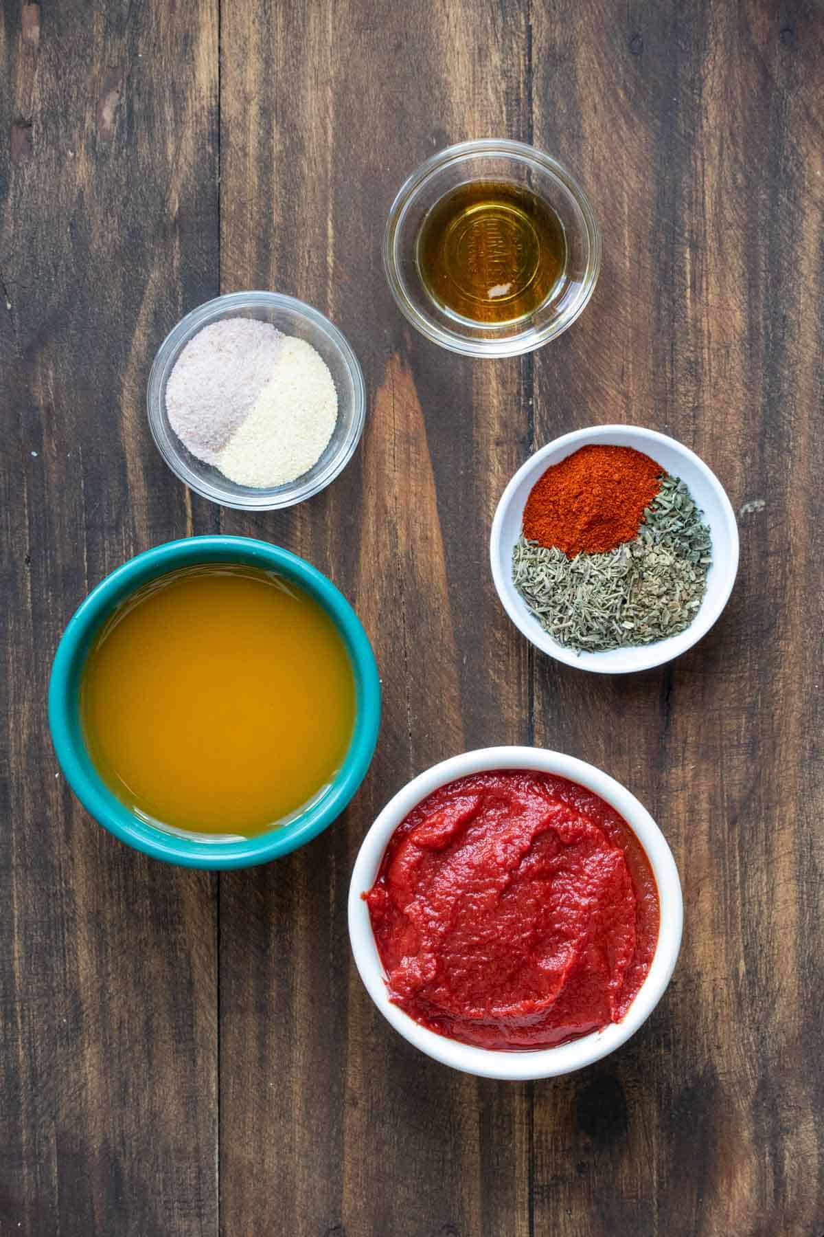 Bowls on a wooden surface with ingredients needed to make pizza sauce