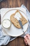 Hand using a knife to spread mayo on a piece of bread