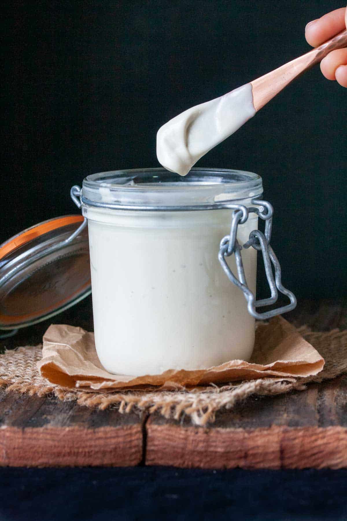 Knife coming out of a jar of homemade mayo with mayo on it