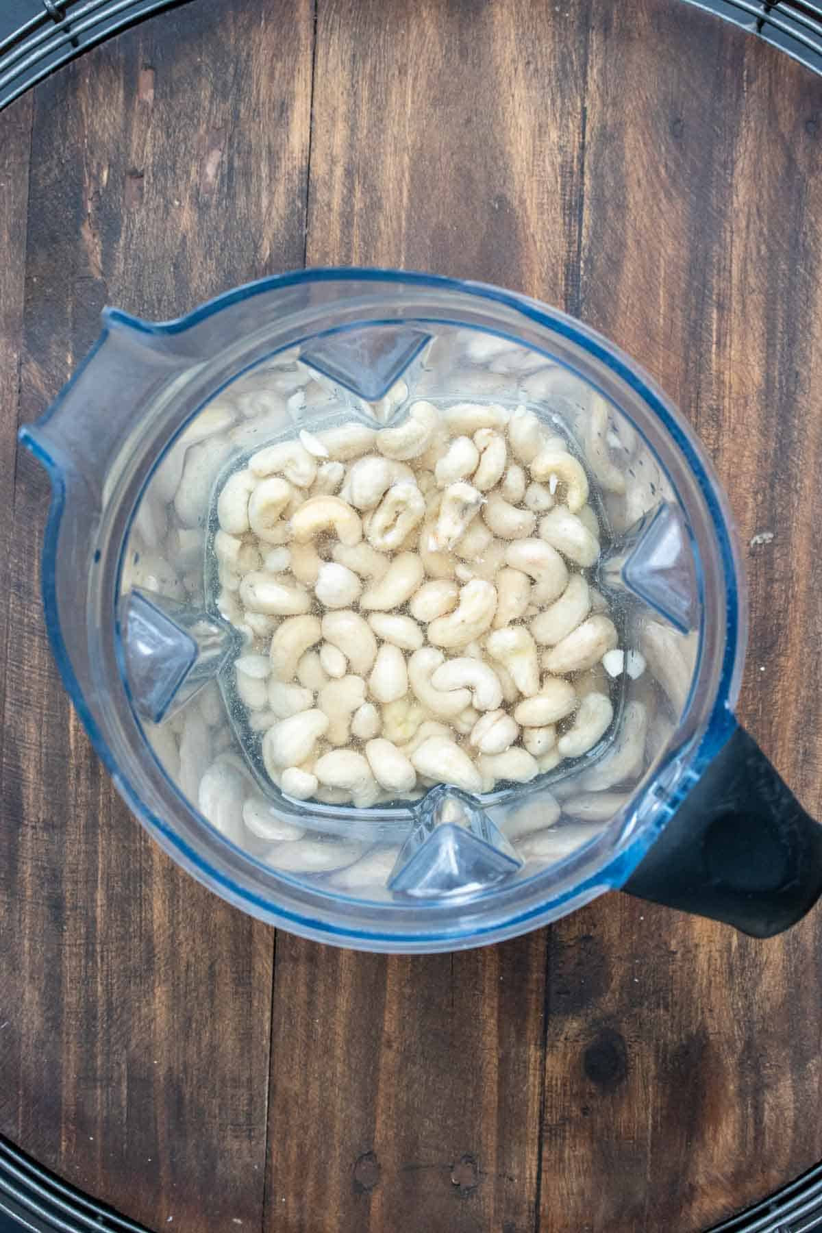 Top view of a blender with water and cashews in it