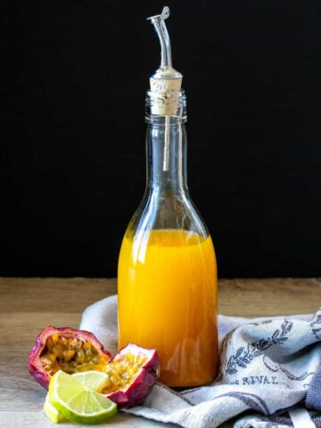 A tall glass bottle filled with passion fruit syrup and closed with a cork with a pour spout