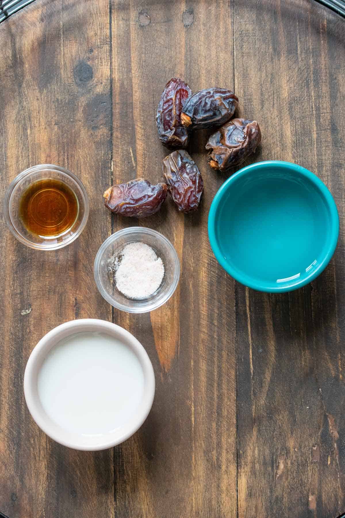 Dates, water, milk, salt and vanilla on a wooden table