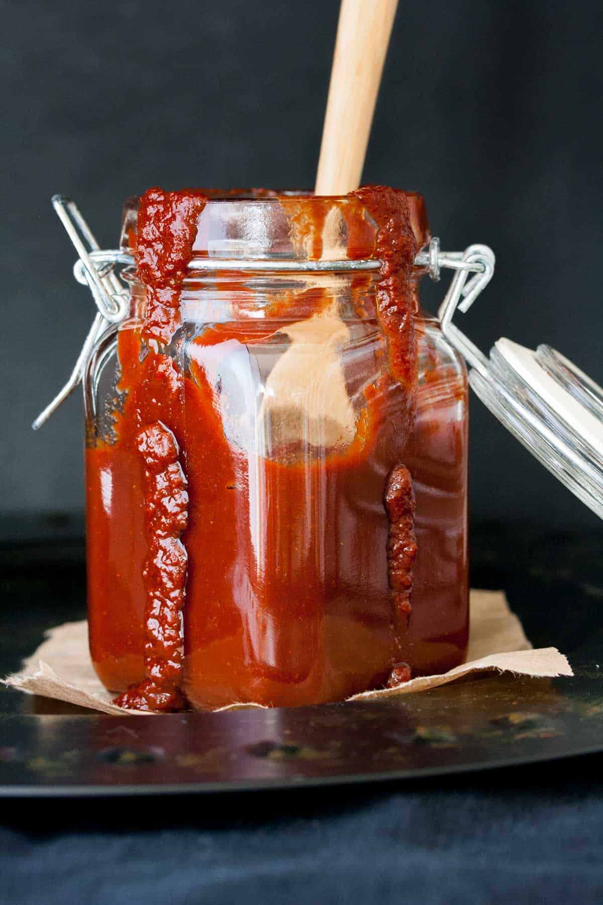 Glass storage jar with bbq sauce in it and running down the sides