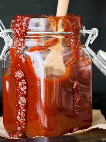 BBQ sauce inside a glass storage jar one a piece of parchment paper