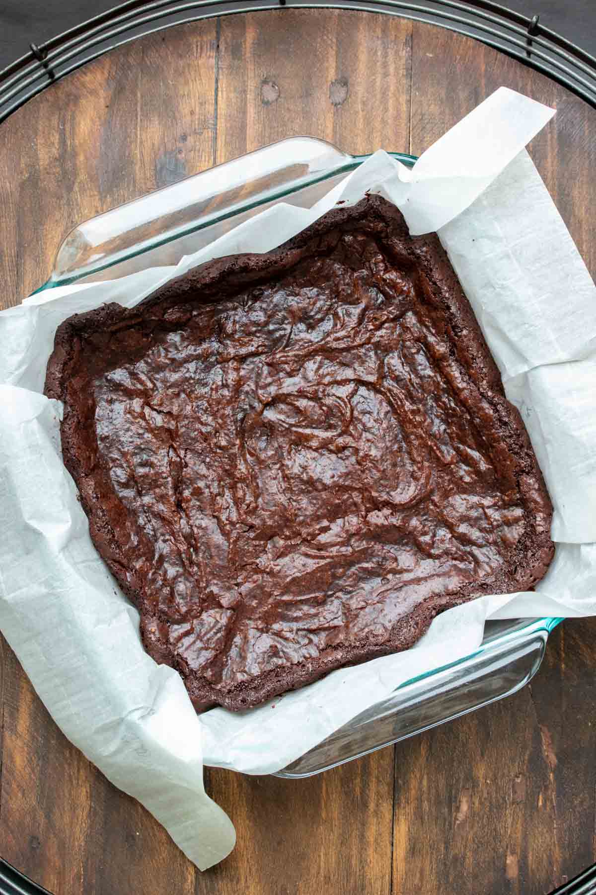 Top view of baked brownies in a square baking dish with parchment.