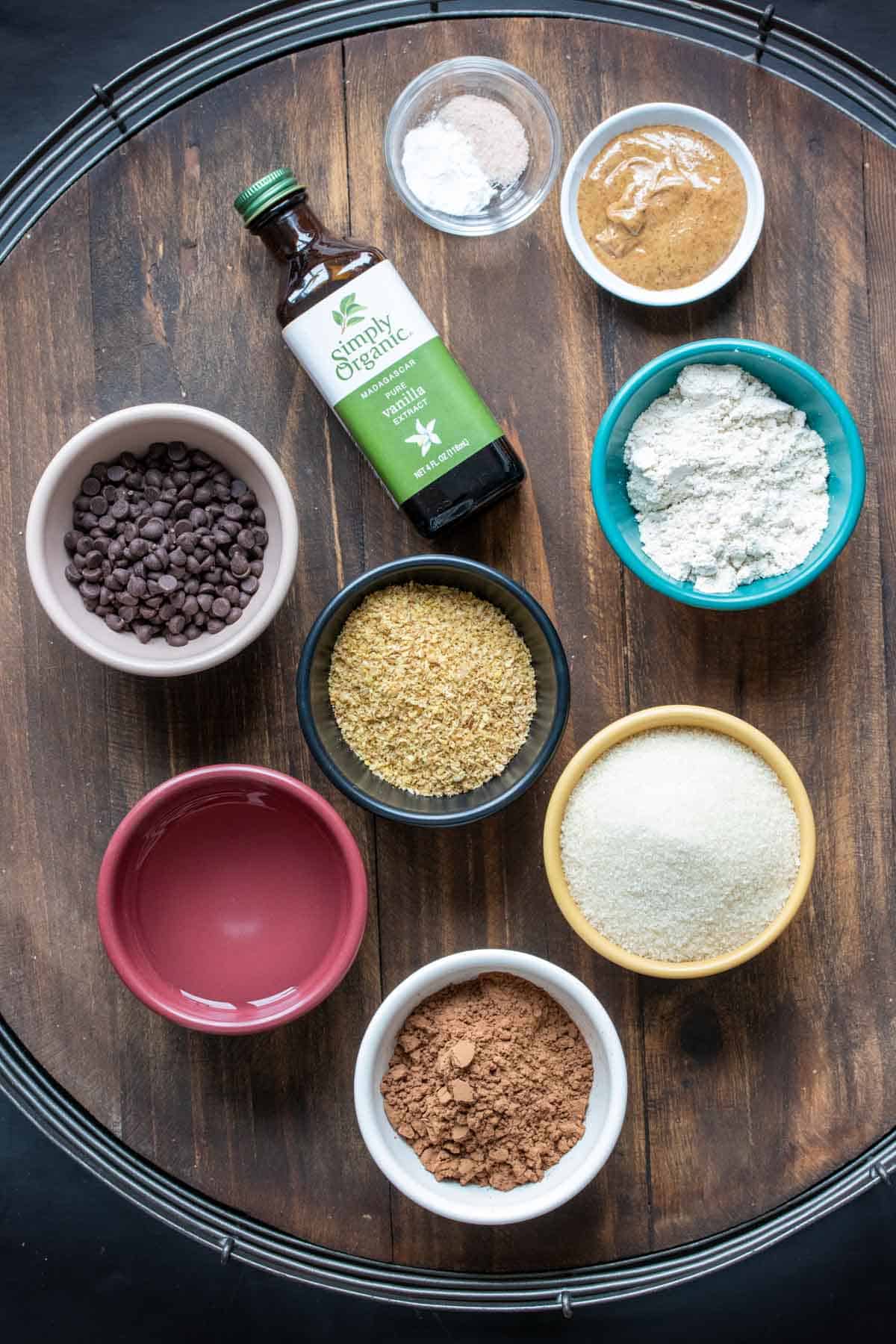 Bowls on a wooden surface filled with ingredients to make brownies.