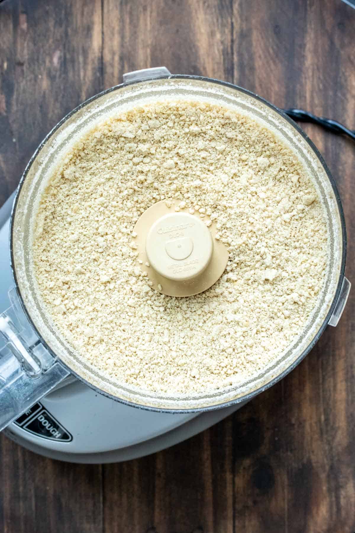 Pulsed cashews in a food processor being made into vegan Parmesan
