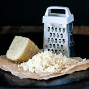 A photo of a pile of grated Parmesan next to a grater.