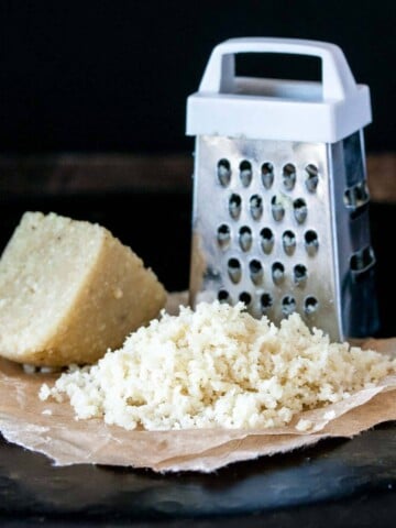 A photo of a pile of grated Parmesan next to a grater.