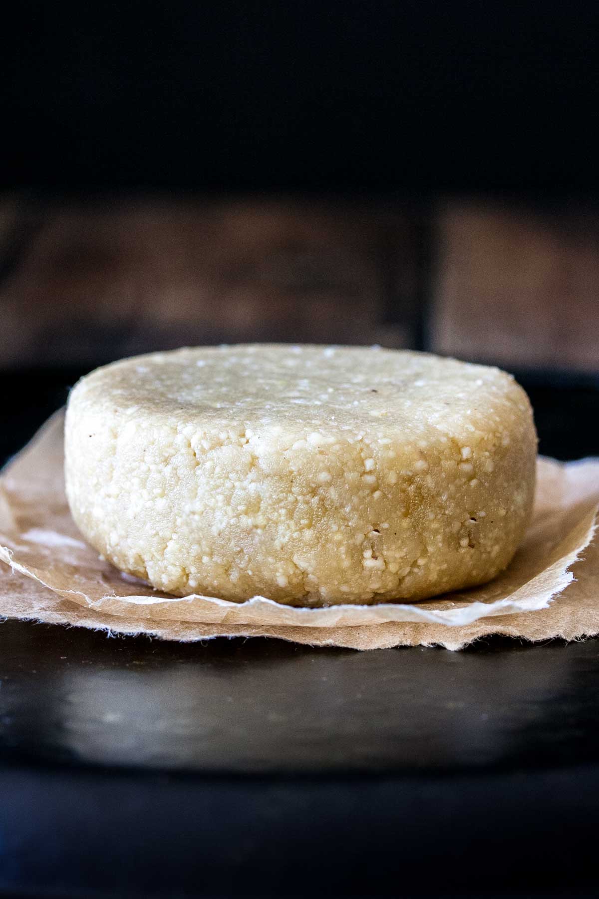 A round block of Parmesan cheese on a piece of parchment paper