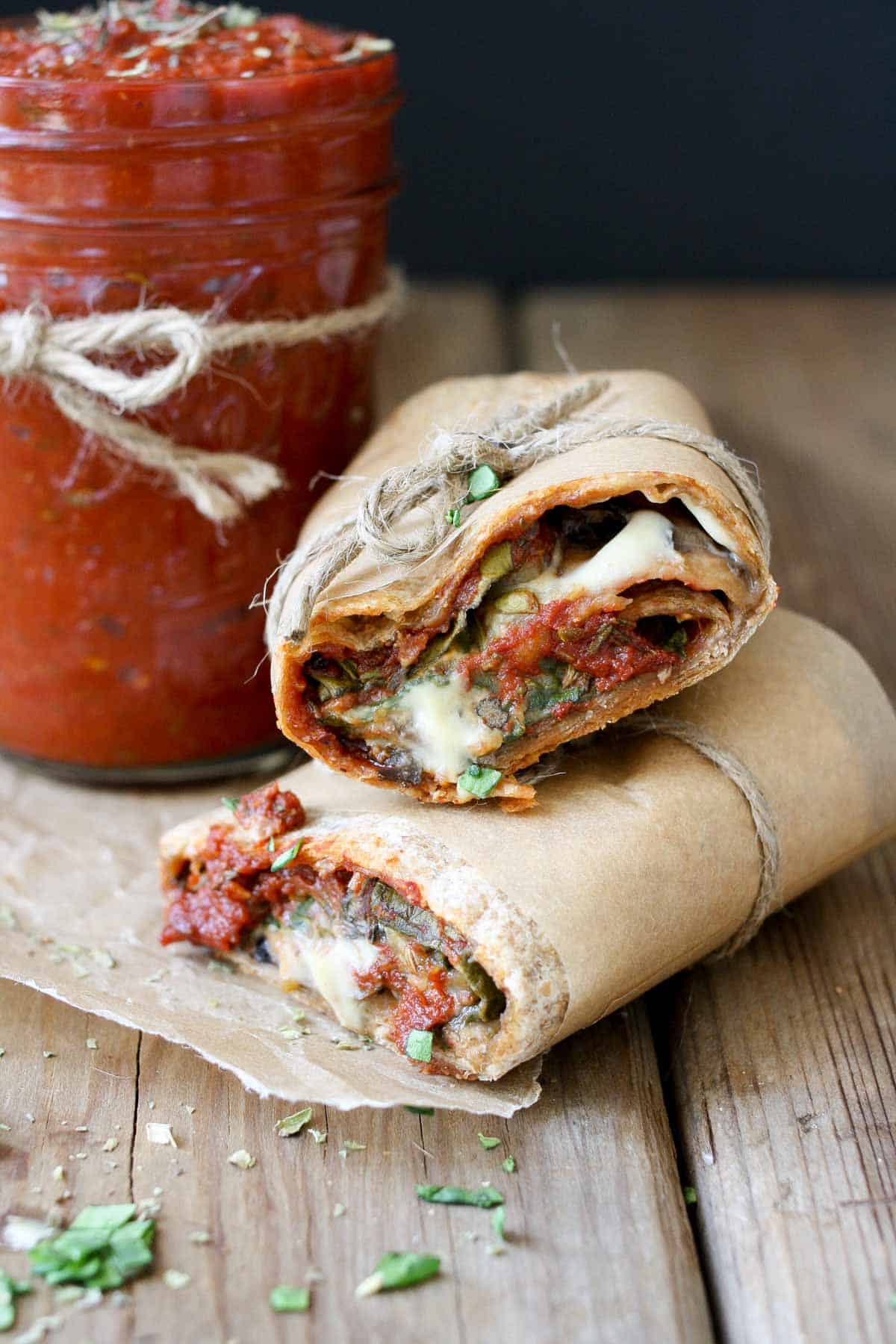 A pizza wrap cut in half and laying on a wooden surface