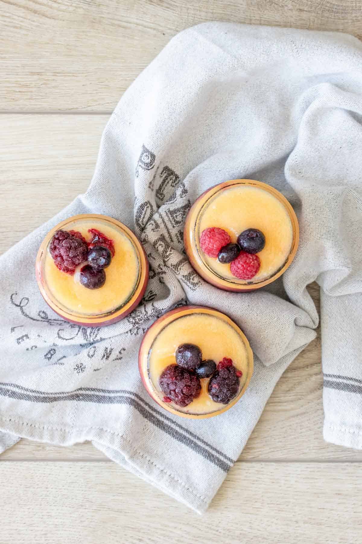 Top view of three jars filled with orange wine slushie topped with fruit