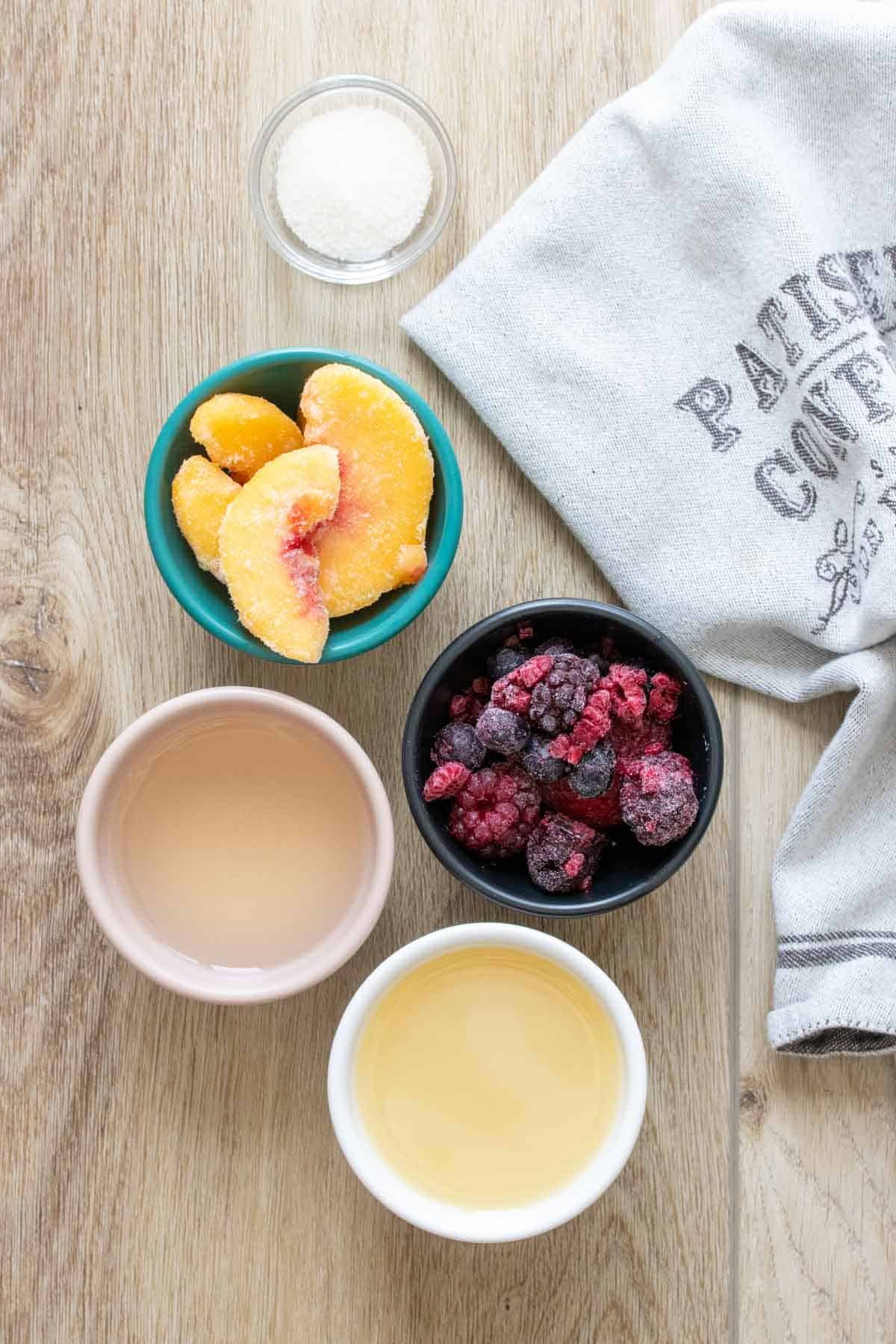 Bowls with frozen fruit, wine and lemon juice on a wooden surface