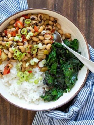 Top view of a bowl with white rice, black eyed peas and greens