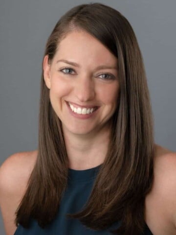 Photo of a woman with long brown hair and dark top smiling