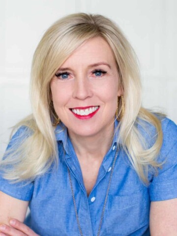 A women with blond hair and red lipstick in a blue button down and hoop earings