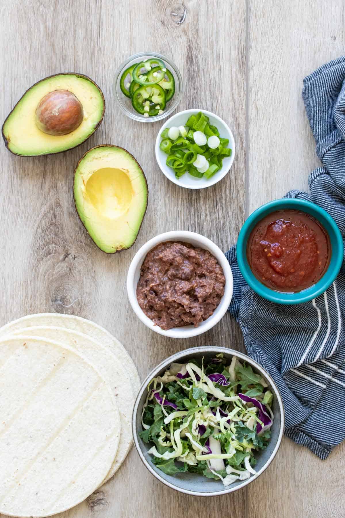 A collection of taco ingredients on a wooden surface.