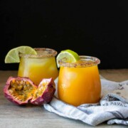 Two glasses with orange drinks in them and limes on the rim