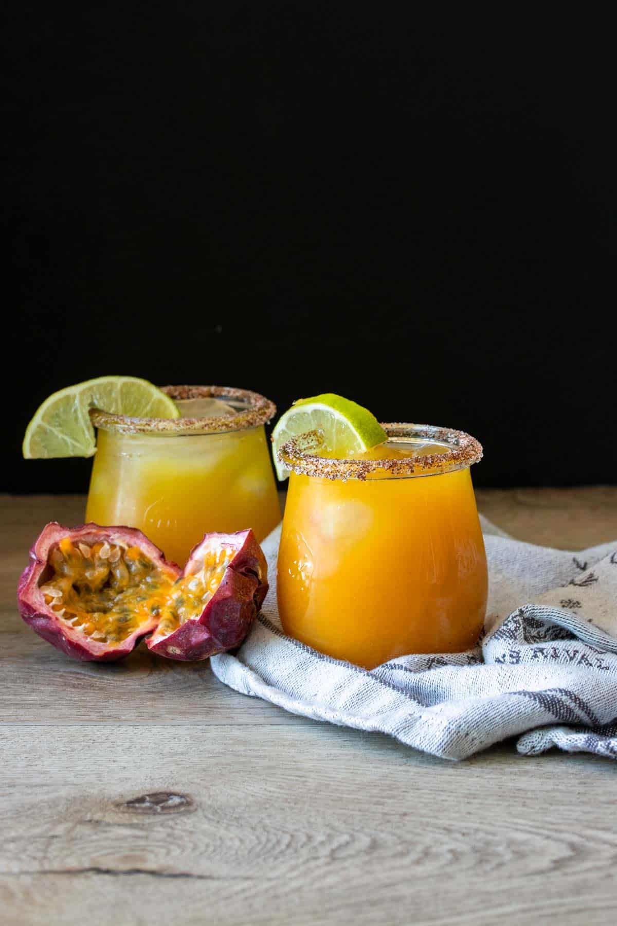 Two glasses with orange drinks in them and limes on the rim