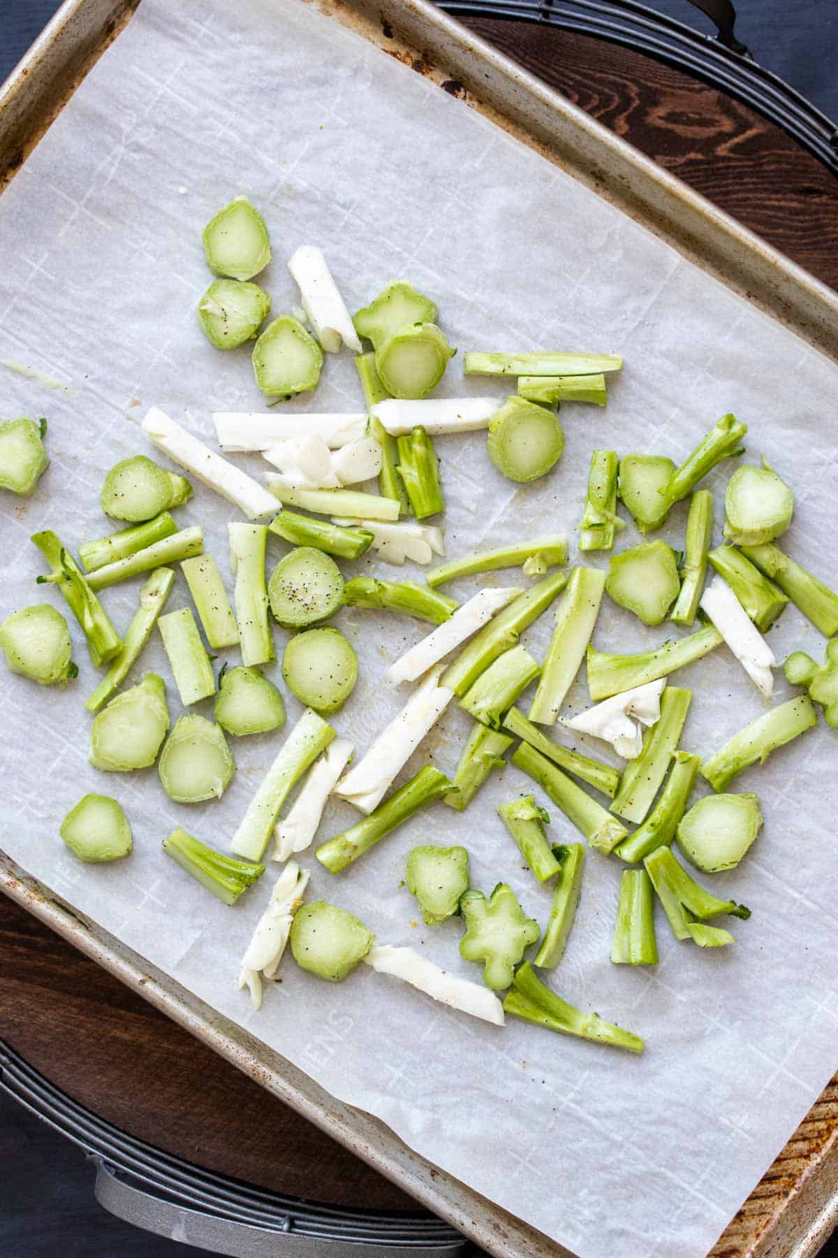 Parchment lined cookie sheet with slices of cauliflower and broccoli stalks