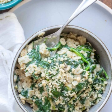 Spoon in a bowl filled with spinach oatmeal on a grey plate