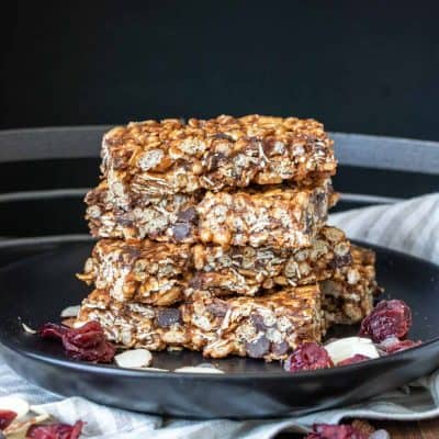A stack of granola bars on a black plate laying on a kitchen towel