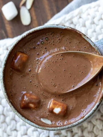 The top view of a mug of hot chocolate with marshmallows and a spoon getting a sip