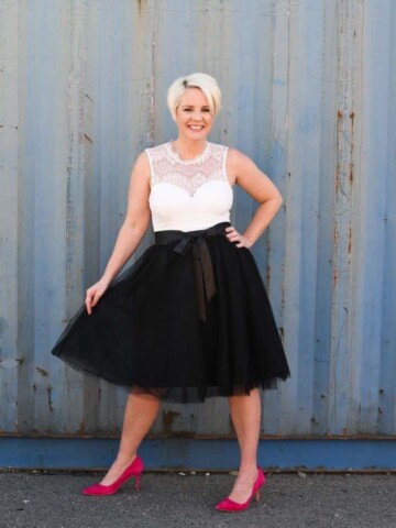 A woman in a black skirt and white shirt standing with her hand on her hip