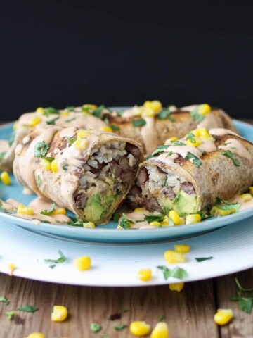 A rice and bean burrito cut in half laying on a blue plate