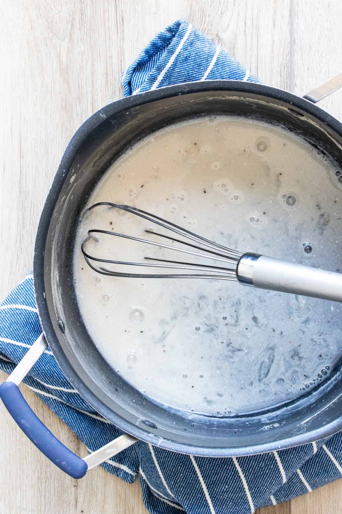 Whisk mixing up a carbonara sauce in a pot