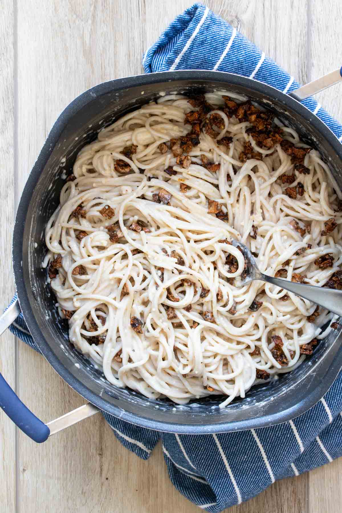 Pot with spaghetti carbonara and portobello bacon being mixed