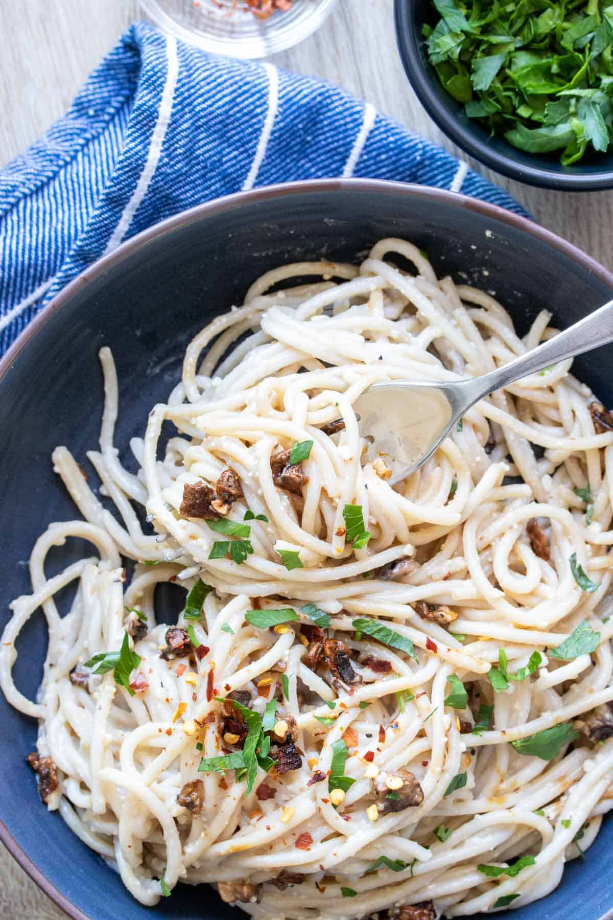 Fork twirling around spaghetti carbonara in a blue bowl