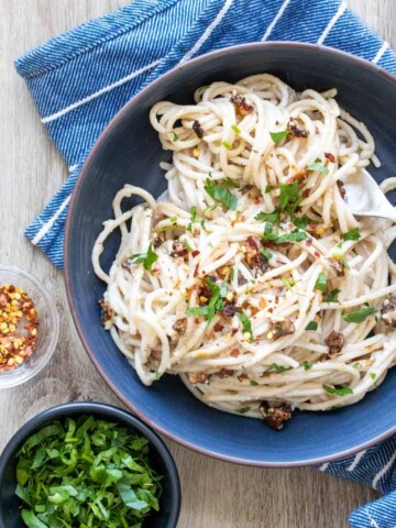 Blue bowl with carbonara pasta inside on a blue striped towel