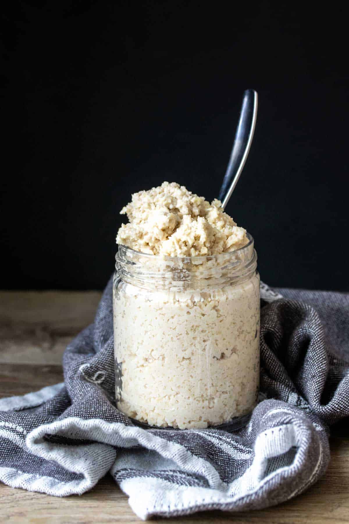 A glass jar filled with a feta cheese mixture and a metal spoon