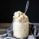 A spoon in a glass jar filled with a homemade feta cheese mixture.