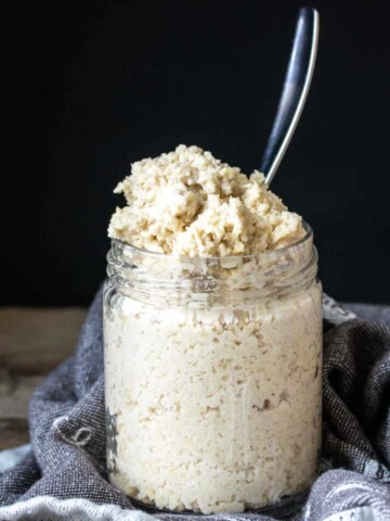 A spoon in a glass jar filled with a homemade feta cheese mixture.