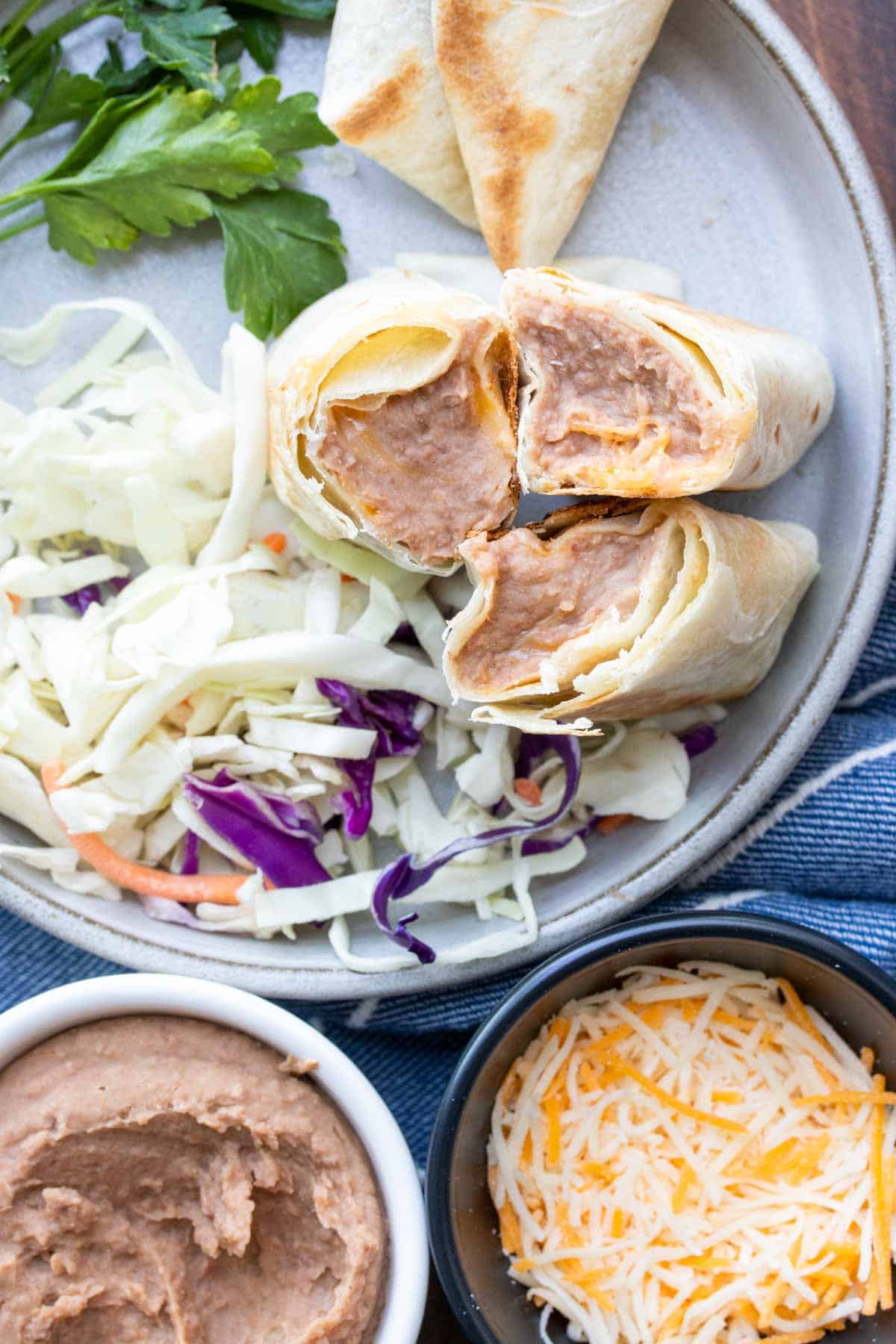 Three halves of a bean and cheese burrito sitting on a grey plate.