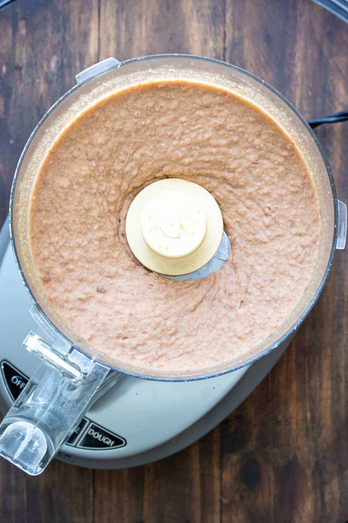 Top view of food processor with pureed pinto beans inside