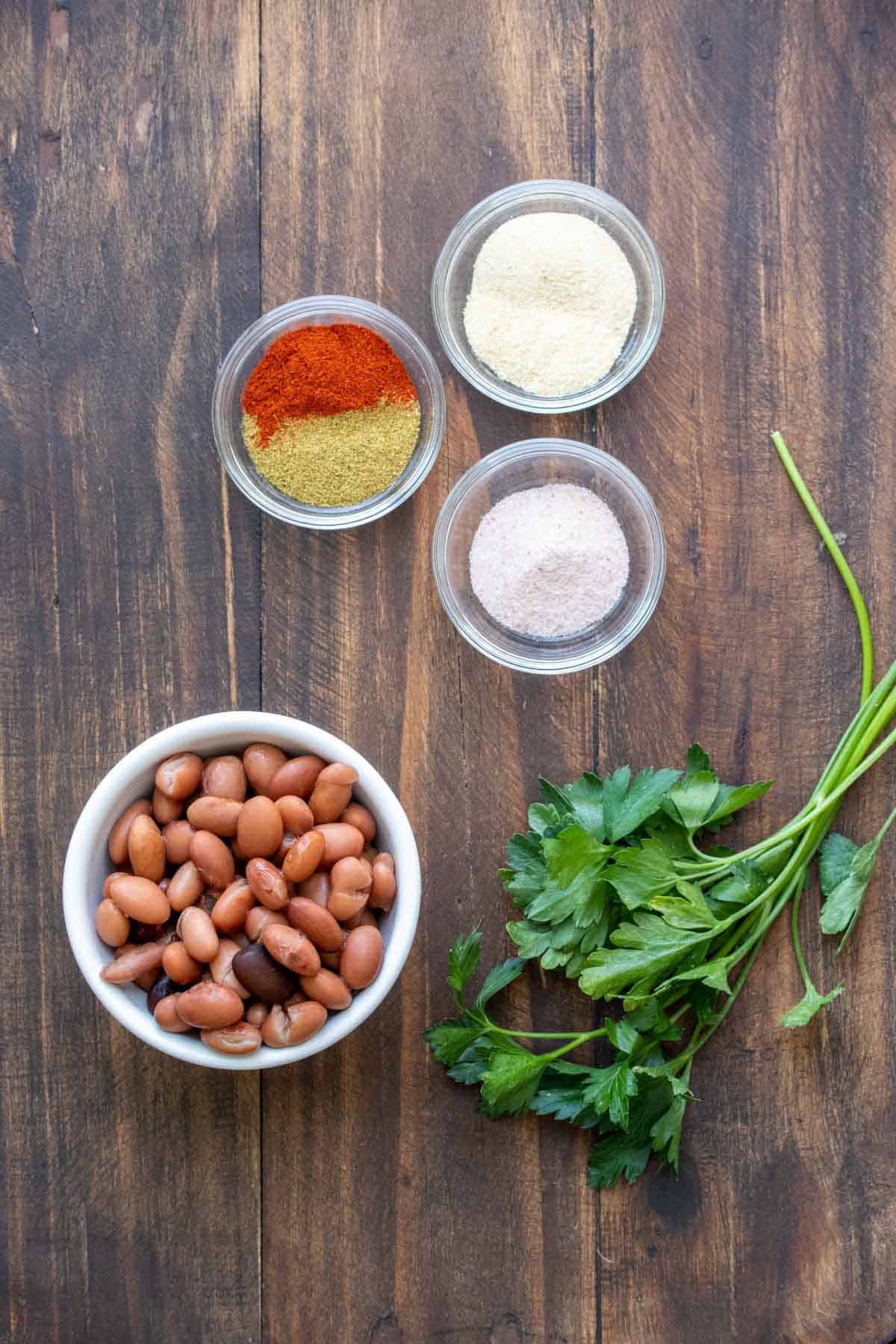Bowls of beans, spices and fresh cilantro on a wooden surface