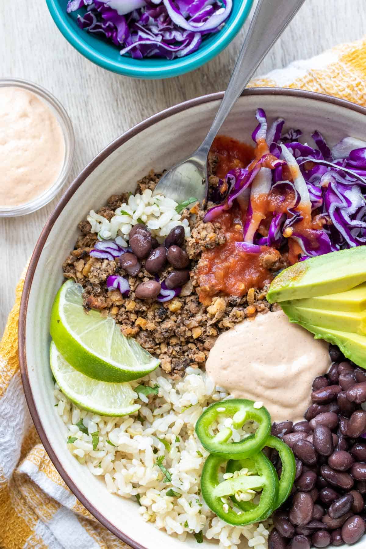 A close up of a loaded up taco bowl with a fork getting a bite out of it