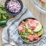 Watermelon salad with feta and mint in a grey bowl next to bowls of ingredients in it.