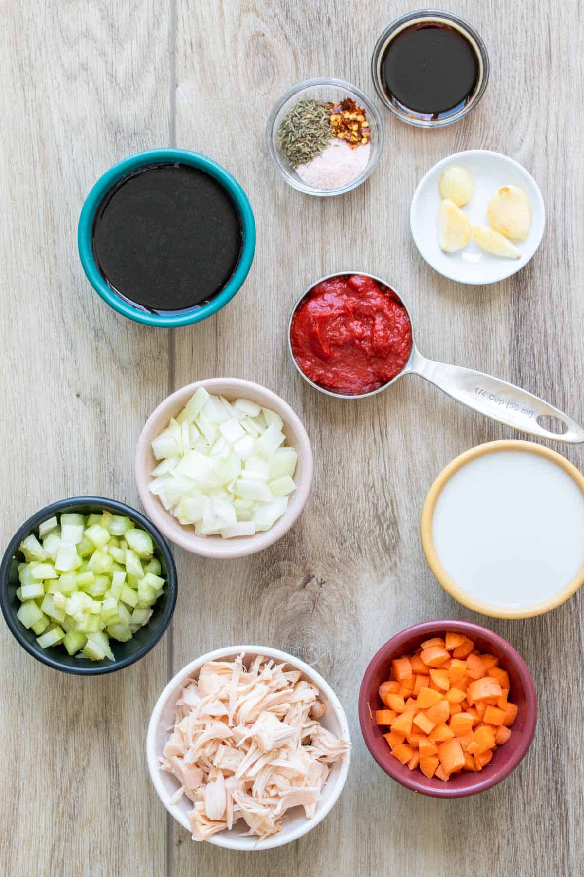 Bowls of ingredients needed to make a vegetable bolognese sauce on a wooden surface