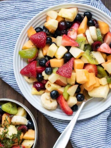 Fruit salad in a bowl on a blue striped towel on a wooden surface