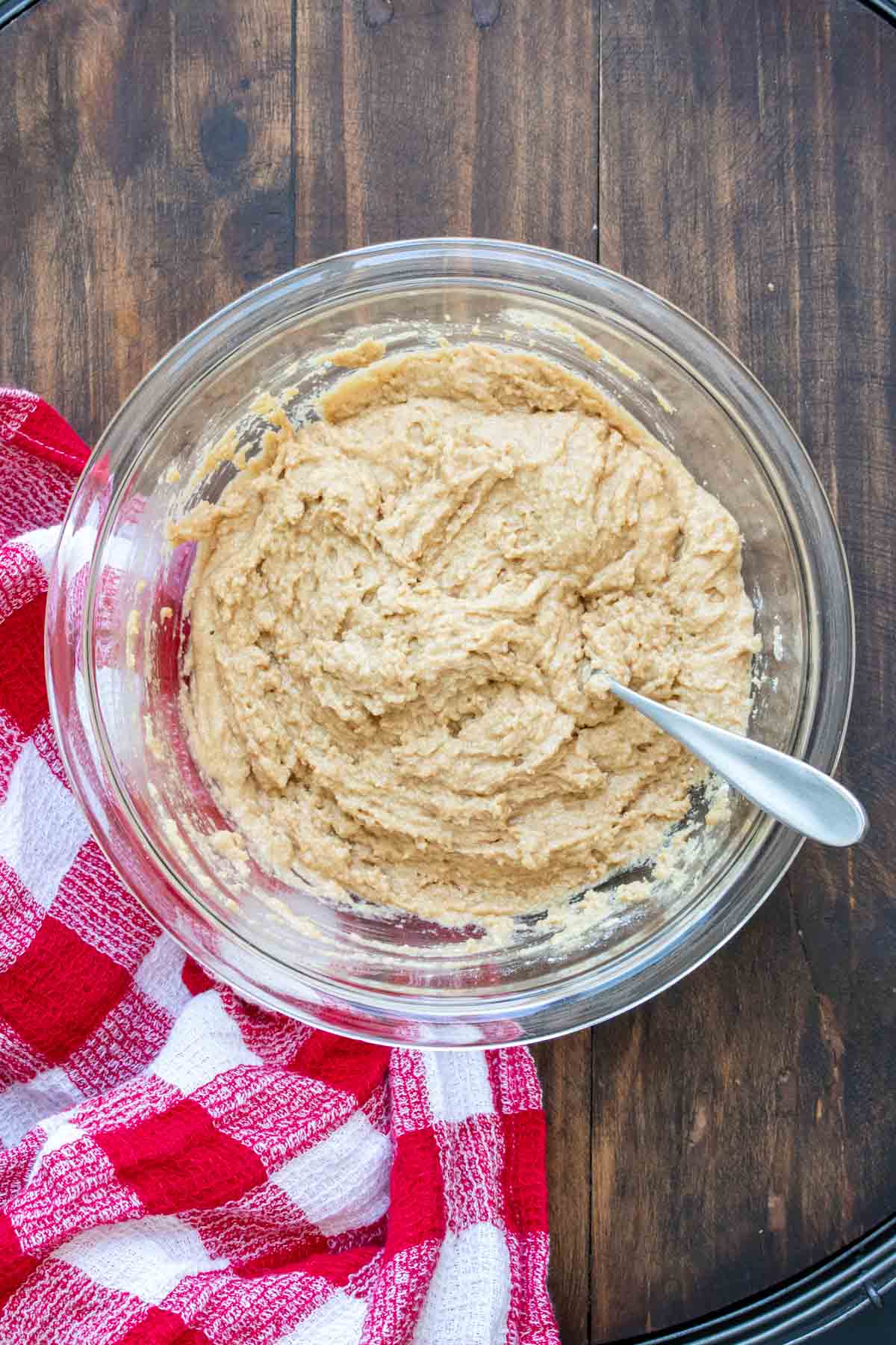 Spoon mixing a dough in a glass bowl