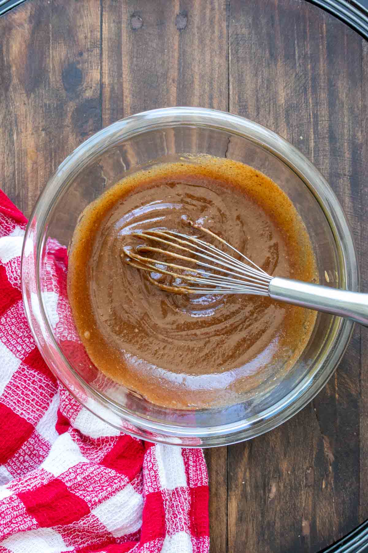 Whisk mixing a caramel like sauce in a glass bowl