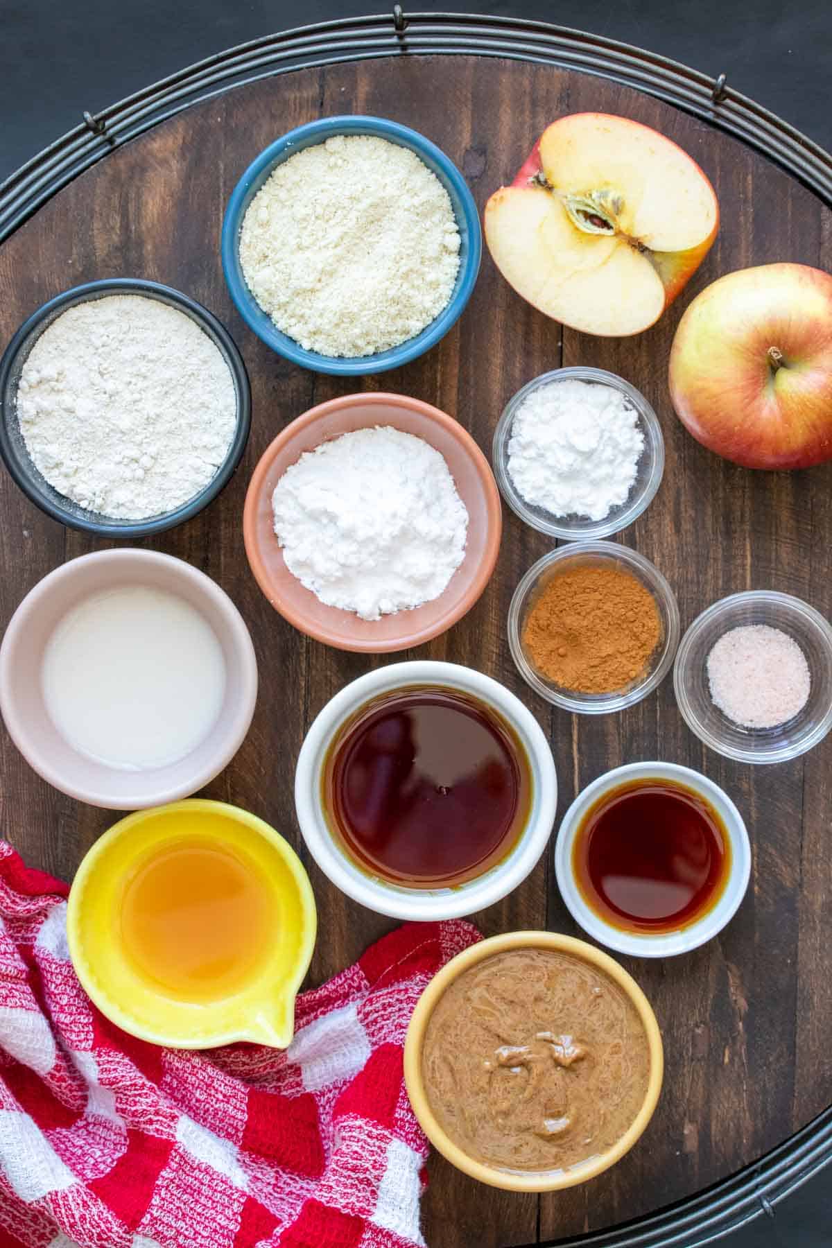 A wooden tray filled with bowls with ingredients to make a vegan apple cobbler.