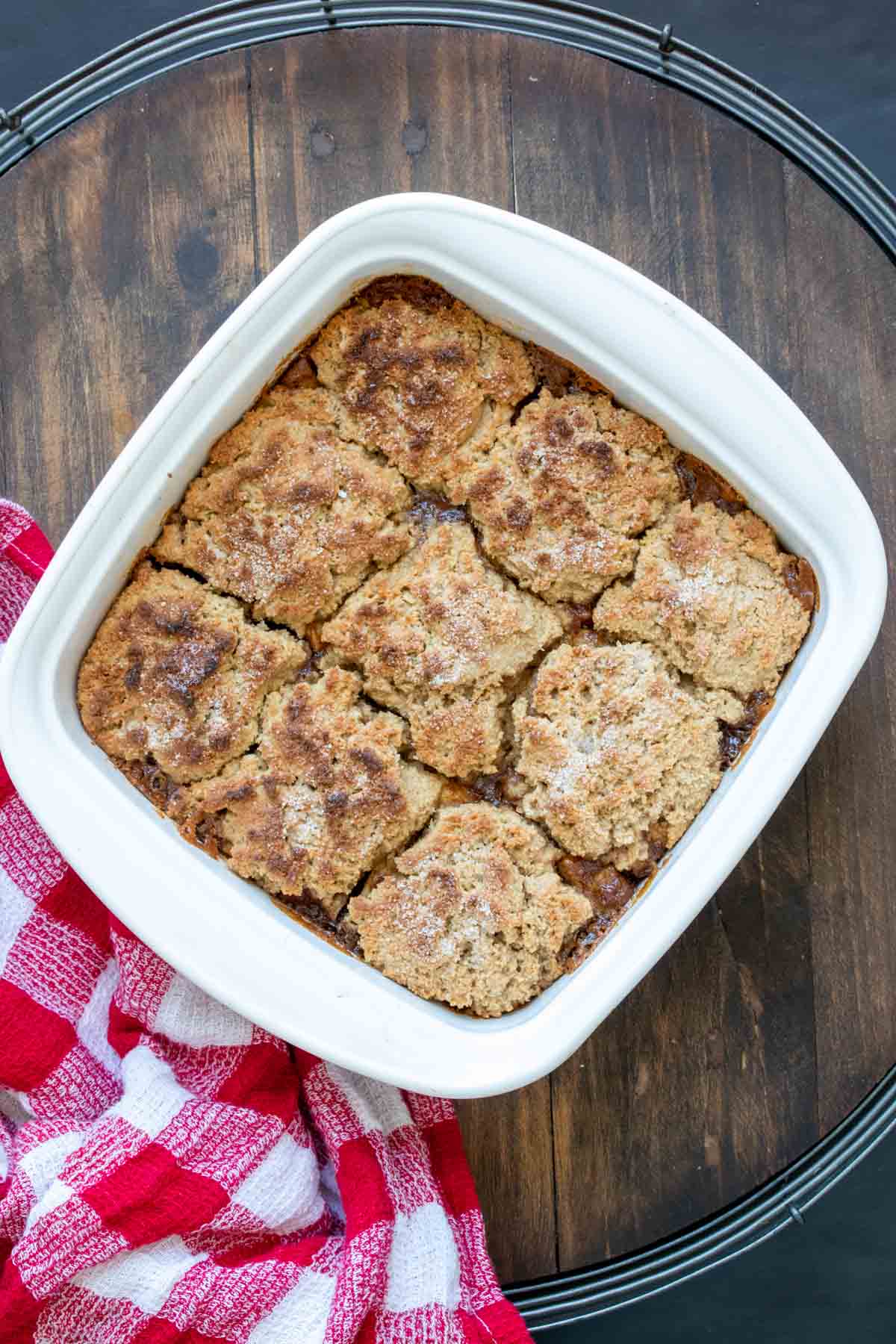 Top view of a baked apple cobbler in a white square baking dish