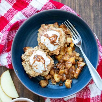 Dark blue bowl filled with apple cobbler on a red checkered towel